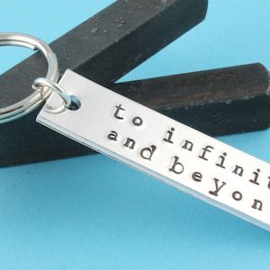 May include: Silver keychain with a rectangular tag that reads "to infinity and beyond".