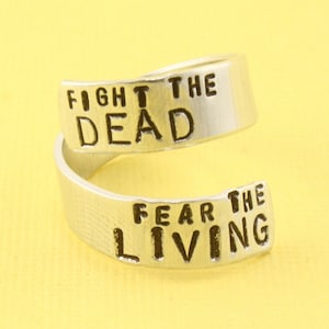 Può includere: Un anello d'argento con le parole "Fight the Dead" e "Fear the Living" incise su di esso.