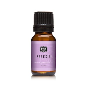 May include: A small amber glass bottle with a black cap, containing Freesia scented premium fragrance oil. The label is purple with white text that reads "P&J Fragrances" and "Freesia Premium Fragrance Oil 10 ml".