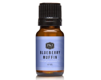 Puede incluir: Una botella de vidrio ámbar de 10 ml con una tapa negra, que contiene aceite de fragancia con aroma a muffins de arándanos. La etiqueta es azul y blanca con el texto "Blueberry Muffin" y "P&J Trading" en negro.