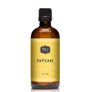 May include: A brown glass bottle with a black cap, containing a yellow liquid. The label is yellow with black text that reads "P&J Trading", "Cupcake", "Fragrance Select", "Premium Fragrance Oil", and "100 ml Premium".