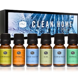 May include: A set of six 10 ml essential oil bottles in a box. The bottles are labeled with different scents: Lemongrass, Orange, Fresh Cotton, Aloe, Clean & Fresh, and Bamboo. The box has a blue background with the text "CLEAN HOME" and "FRAGRANCE COLLECTION".