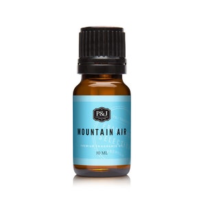 May include: A 10 ml amber glass bottle of Mountain Air premium fragrance oil. The bottle has a black cap and a blue label with white text that reads "P&J Fragrance Selection, Mountain Air, Premium Fragrance Oil, 10 ml".