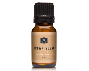 Puede incluir: Una pequeña botella de vidrio ámbar de aceite perfumado de azúcar moreno. La etiqueta dice "Brown Sugar Selection" con la marca "P&J Trading". La botella tiene una tapa negra y contiene 10 ml de aceite.