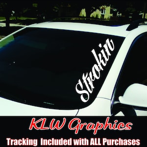 May include: White vinyl decal with the word "Strokin" in a cursive font on a white car windshield. The decal is angled diagonally from the top left corner to the bottom right corner of the windshield. The text "KLW Graphics" is in red text below the decal.
