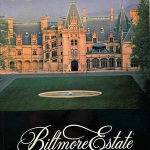 May include: A guide to Biltmore Estate, a large, ornate, stone mansion with a slate roof. The mansion is surrounded by a lush green lawn with a small fountain in the center. The text "Biltmore Estate" is written in a cursive font on a black background.