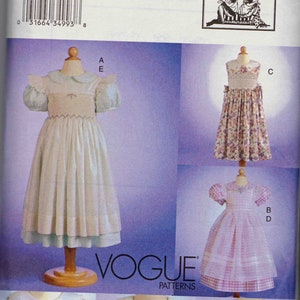May include: A sewing pattern for four different girls' dresses. The pattern is for sizes 2, 3, and 4. The dresses are all white with different floral patterns. The pattern is from Vogue Patterns and is designed by Teresa Layman.