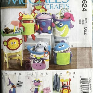 May include: A McCall's Crafts sewing pattern for making fabric storage containers in various animal designs. The pattern includes instructions for a monkey, shark, cow, and other animal-themed bins. The pattern number is M6624.