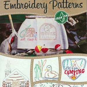 May include: An "Aunt Martha's" embroidery pattern booklet with a "Great Outdoors" theme. The cover features embroidered designs of fishing and camping scenes, including a cabin, duck, bear, and the text "Let's go CAMPING".