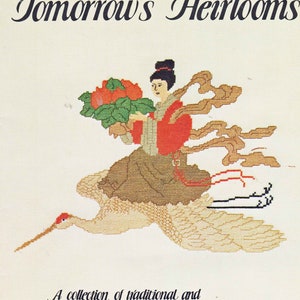 May include: A book cover featuring a woman in a red and brown kimono riding a white crane with a bouquet of red flowers. The title of the book is "Tomorrow's Heirlooms" and the text below reads "A collection of traditional and contemporary designs for today's needlework."