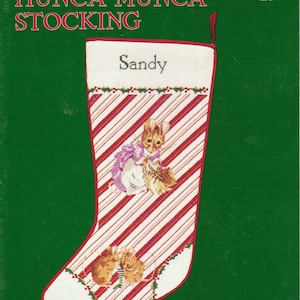 May include: A white stocking with red and white candy cane stripes. The stocking features a cross-stitch design of three mice from Beatrix Potter's "Hunca Munca" book. The stocking is personalized with the name "Sandy".