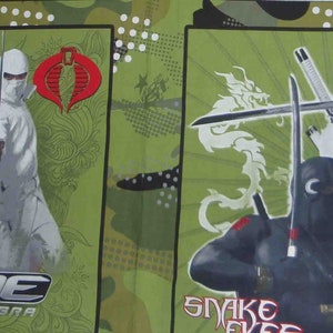 May include: A green and white fabric with two panels featuring characters from the G.I. Joe: The Rise of Cobra movie. The left panel shows a black-clad character with a sword and the text "G.I. Joe The Rise of Cobra". The right panel shows a white-clad character with a sword and the text "Storm Shadow Snake Eyes".