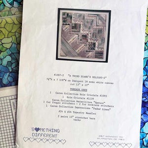 May include: A cross stitch pattern for a design called "A Third Diane's Delight-2". The pattern is 7 3/8 inches wide by 7 1/4 inches tall and is meant to be stitched on Zweigart 18 mono white canvas. The pattern includes a list of threads and materials needed to complete the project, including Caron Collection Soie Cristale, Caron Collection Waterlilies, Caron Collection Impressions, tapestry needles, and stretcher bars.