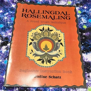 May include: A vintage instruction book titled "Hallingdal Rosemaling" with a round brush technique. The cover is orange with a floral design in yellow, green, and blue. The book is a beginner's guide by Audine Schatz.