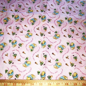 May include: Pink fabric with a repeating pattern of Peter Rabbit illustrations. The fabric features a white outline of Peter Rabbit and a green plant in a pot. The text "Peter Rabbit ran and ran!" is repeated throughout the fabric.