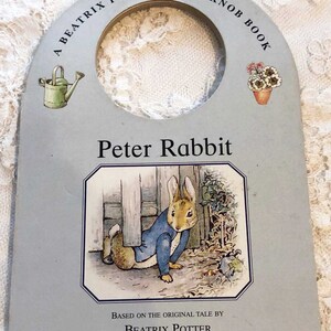 May include: A blue and white door knob book featuring Peter Rabbit, based on the original tale by Beatrix Potter.