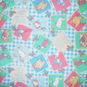 May include: A blue and white checkered fabric with a repeating pattern of pink and green squares. Each square features a different illustration from the book "The Tale of Peter Rabbit" by Beatrix Potter. The illustrations include Peter Rabbit, Jemima Puddle-Duck, and Mrs. Tiggy-Winkle. The fabric is perfect for quilting, sewing, or crafting.