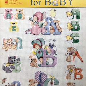 May include: Cross-stitch pattern titled "alphabets for Baby" featuring colorful designs of the letters A, B, and C with teddy bears, chicks, and other baby-themed illustrations. The pattern includes 15 designs by Linda Gillum.
