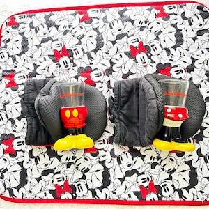 May include: Two black oven mitts with red and white polka dot Mickey Mouse cups on a black and white Minnie Mouse print kitchen mat.
