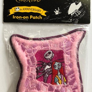 May include: A pink and purple iron-on patch featuring Jack Skellington and Sally from the movie "The Nightmare Before Christmas". The patch is a 10th anniversary edition and is exclusive to Claire's.