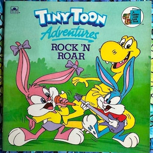 May include: A book cover featuring the Tiny Toon Adventures characters Buster Bunny, Babs Bunny, and Dizzy Devil. The title of the book is "Rock 'n Roar".