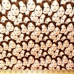 May include: A white fabric with a repeating pattern of brown faces. The faces are all the same, with a serious expression and brown hair.