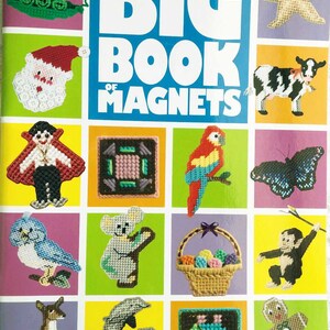 May include: A book cover titled "BIG BOOK OF MAGNETS" featuring various plastic canvas magnet designs. Designs include a Santa, a cow, a parrot, a butterfly, a koala, a basket of eggs, a kangaroo, dolphins, and a gingerbread man. The book is by Annie's Plastic Canvas.
