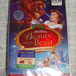 May include: A VHS tape of the Disney movie Beauty and the Beast: The Enchanted Christmas. The cover features Belle and the Beast in a snowy winter scene with a red and gold background. The title is in a gold font with a red border. The tape is available for purchase at Toys"R"Us for $14.99.