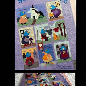 May include: A quilted wall hanging with the text "Fun with Sunbonnet Sue" and illustrations depicting daily activities. The quilt features a lavender background and colorful appliqued figures, including a church, cat, and figures in bonnets.