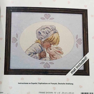 May include: Cross stitch pattern featuring a girl with blonde hair and a white bonnet kissing a white bunny. The pattern is called "Love Notes" and includes a mat. The finished size is 7 1/4 inches by 5 1/4 inches.
