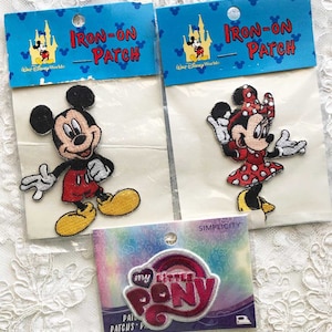 May include: Three iron-on patches featuring Mickey Mouse, Minnie Mouse, and My Little Pony. The Mickey Mouse patch is red and yellow, the Minnie Mouse patch is red and white, and the My Little Pony patch is pink and purple.