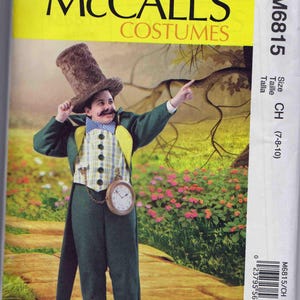 May include: McCall's Costumes pattern for a child's Mad Hatter costume. The ensemble includes a green jacket, pants, vest, and a tall brown hat. A pocket watch hangs from the vest. The pattern size is CH (7-8-10).