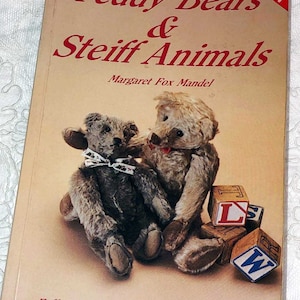 May include: A vintage book titled "Teddy Bears & Steiff Animals" by Margaret Fox Mandel. The cover features two teddy bears and wooden alphabet blocks. The book is a full-color identification and value guide.