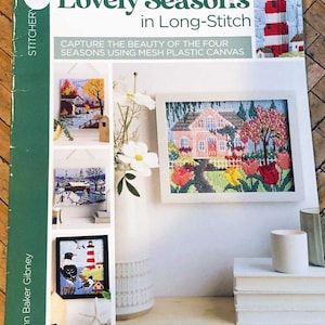 May include: A book cover for a beginner level long stitch embroidery project titled "Lovely Seasons". The cover features four different embroidery designs: a winter scene, a spring scene, a summer scene, and a fall scene. The book is by Conn Baker Gibney.