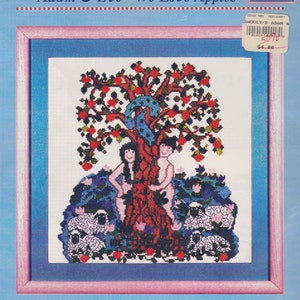 May include: Cross stitch pattern featuring Adam and Eve standing by a tree with red apples. The pattern includes a blue ribbon around the tree and sheep in the foreground. The pattern is titled "Adam & Eve - We Love Apples" and is from Wooly Dreams Design.