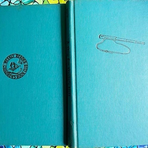 May include: A teal blue hardcover book with the text "Twenty Reader" and "Children's Book Club" in a circle on the front cover. The back cover has a drawing of a telescope with a strap.