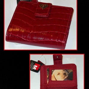 May include: A red, textured wallet with a heart-shaped clasp. The wallet is open, revealing a photo of a dog. The wallet has a tag that says "Accessories".