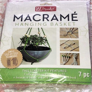 May include: A macrame hanging basket kit with 7 pieces, including 2 rolls of jute cord, 4 decorative beads, and a 16-page instruction book. The kit features a simple step-by-step technique guide.
