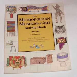 May include: The cover of a book titled "The Metropolitan Museum of Art Activity Book" by OSA BROWN. The book features illustrations of various objects from the museum's collection, including a fish kite, a woven tapestry, a cat, a musical instrument, and a model of a building.