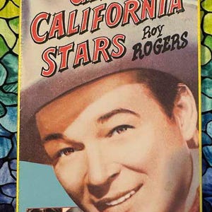 May include: A vintage VHS tape of the movie "Under California Stars" starring Roy Rogers. The cover features a portrait of Roy Rogers in a cowboy hat, with the movie title in red and white lettering. The tape is in its original packaging.