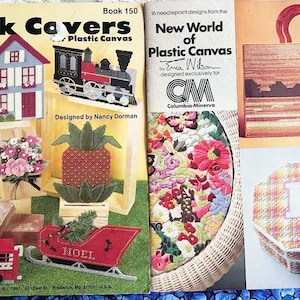 May include: Two plastic canvas needlepoint pattern books. The first book is titled "Brick Covers" and features a snowman, a house, a train, and a pineapple. The second book is titled "New World of Plastic Canvas" and features a floral design, a sunset scene, and a plaid box with the letter "E".