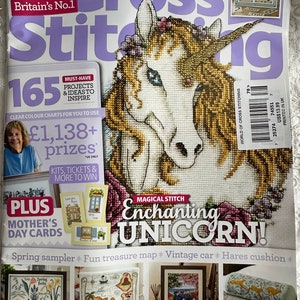 May include: The World of Cross Stitching magazine cover featuring a colorful unicorn cross stitch pattern. The magazine cover also includes a calendar, a spring sampler, a fun treasure map, a vintage car, and a hares cushion.