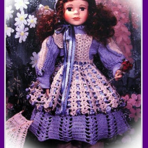 May include: A purple crocheted dress with a white crocheted bodice and a white ribbon tied around the neck. The dress is worn by a doll with long brown hair and a white crocheted hat.