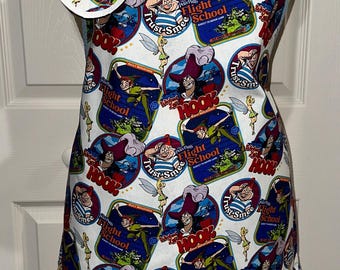 May include: White apron with a blue trim and a pattern of Peter Pan characters, including Captain Hook, Tinkerbell, and Smee. The apron has a pocket and a matching round pot holder.