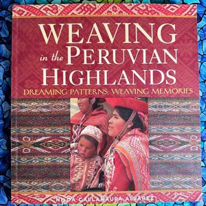 May include: A book titled "Weaving in the Peruvian Highlands: Dreaming Patterns, Weaving Memories" by Nilda Callanaupa Alvarez. The cover features a colorful woven textile pattern and a photo of three women wearing traditional Peruvian clothing.