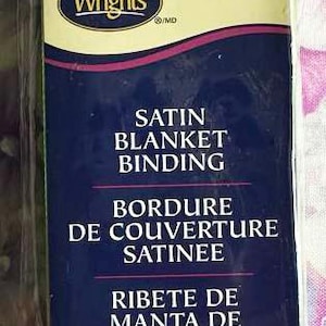 May include: A package of green satin blanket binding. The label includes the brand "Wrights" and the text "SATIN BLANKET BINDING". The package contains 4.75 yards / 4.34 meters of binding.