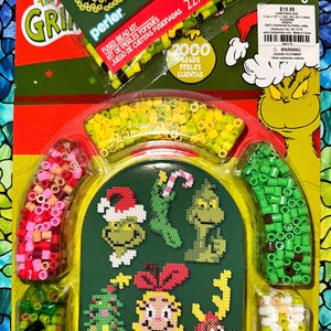 May include: A Perler fused bead kit featuring The Grinch characters. The kit includes various colors of beads and patterns to create Grinch-themed designs. The packaging displays the Grinch and other Christmas-themed characters. The kit contains 2000 beads.
