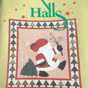 May include: A Christmas-themed quilt pattern with the text "Deck The Halls." The design features a central image of Santa Claus carrying a Christmas tree and holding star-shaped ornaments. The border includes alternating green and brown Christmas trees.