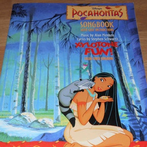 May include: A color-coded songbook for the Disney movie Pocahontas, featuring a cartoon image of Pocahontas with a raccoon on her shoulder. The book cover has the title "Pocahontas Songbook" and the text "Xylophone Fun!"