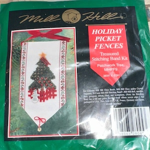 May include: A sealed package for a Mill Hill Holiday Picket Fences cross-stitch kit. The kit features a Patchwork Tree design with a Christmas tree, snowman, and picket fence. The package includes beads, floss, and instructions. The dimensions are 36 inches wide by 63 inches high.